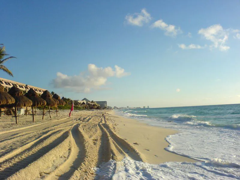 Palapa umbrellas along a wide sandy beach in Cancún.