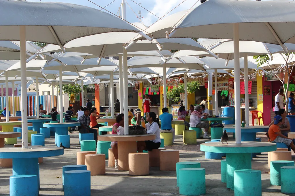 Colorful tables under white umbrellas at the food stalls of Parque de las Palapas, Cancún.