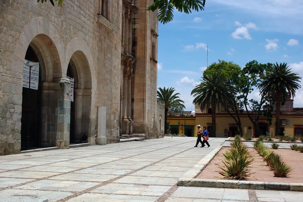Stone arches and a garden beside a colonial building in Oaxaca.