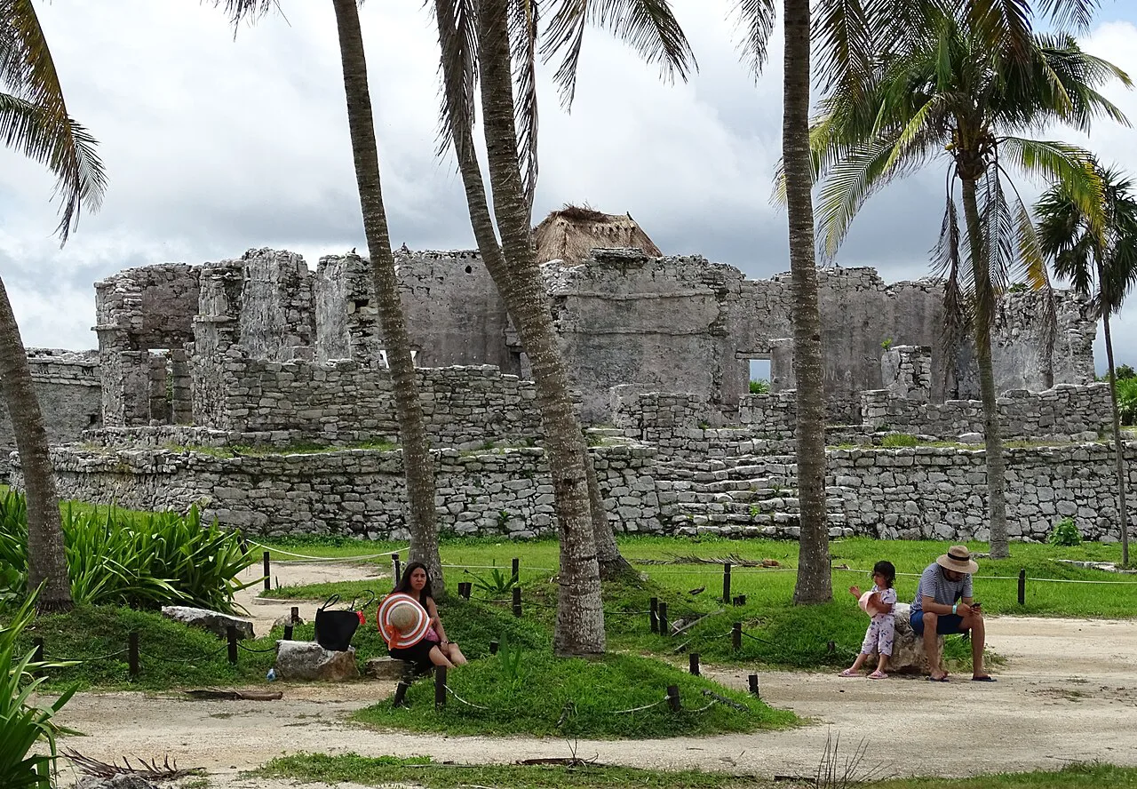 Stone Maya buildings among palm trees at the Tulum archaeological site.